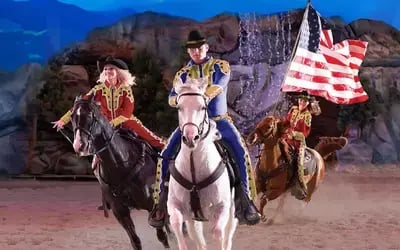 Horseback riders race across the stadium it Dolly Parton's Stampede