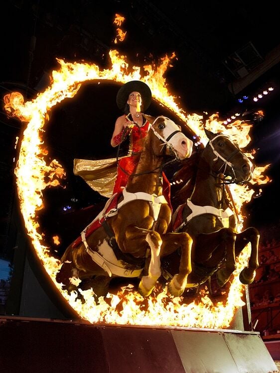 Stampede performer riding horses through a ring of fire