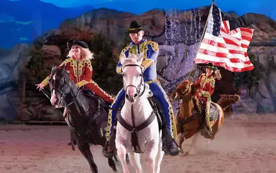 Horseback riders race across the stadium it Dolly Parton's Stampede