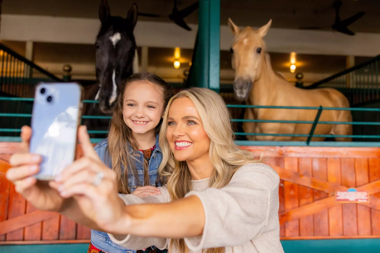 Woman and child taking a photo in front of a horses