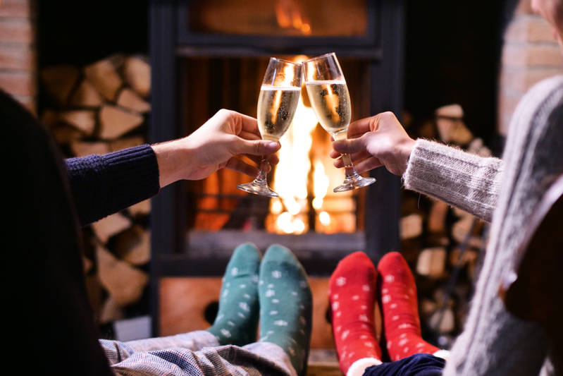 couple holding glasses of champagne in front of a fire