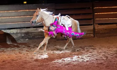 smiling trick rider on the side of a horse